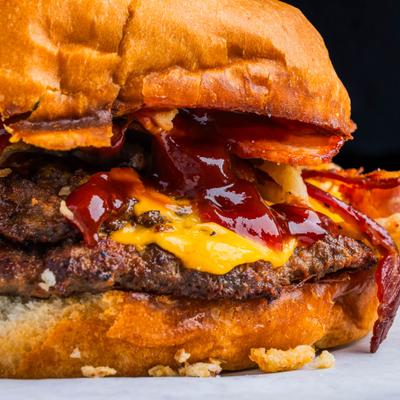 Burger with bacon, cheddar, crispy onions and BBQ sauce, close-up.