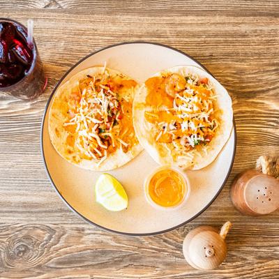 Shrimp Tacos served with a dip, alongside a drink, top view.