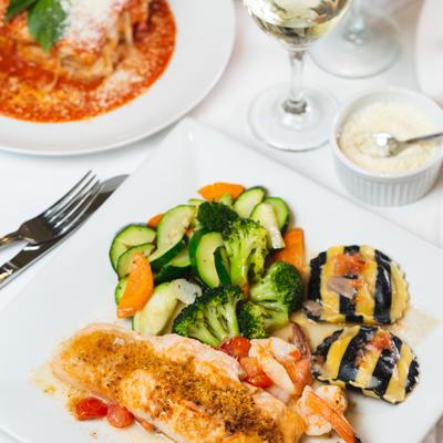 Salmón Oreganatto, served with a glass of white wine, other dishes