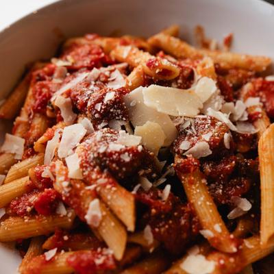 Spicy penne pasta with sausage, Parmesan, and tomato-based sauce.