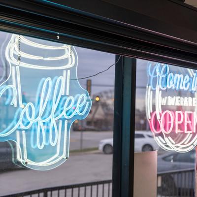 Neon coffee sing and neon open sign in a storefront window.
