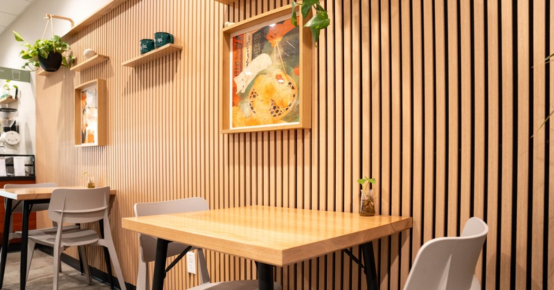 interior dining space showing a square table and two chairs, wall art, and plants