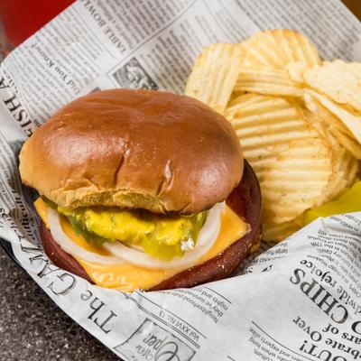 Fried Bologna sandwich, with cheese, onion and pickles, with a side of potato chips.