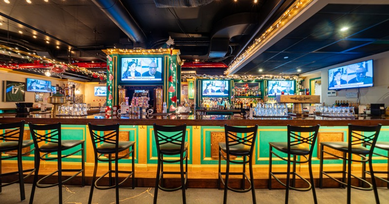 A large, colorful bar and black barstools