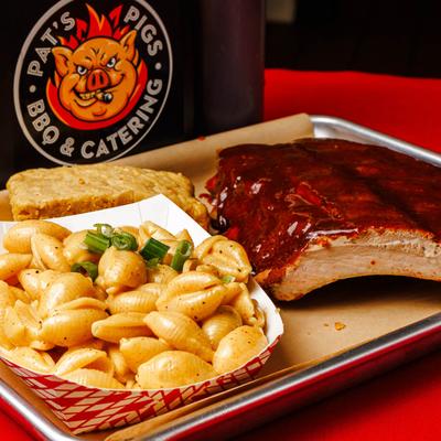 Half rack pork ribs topped with BBQ sauce, with sides of macaroni and corn bread.