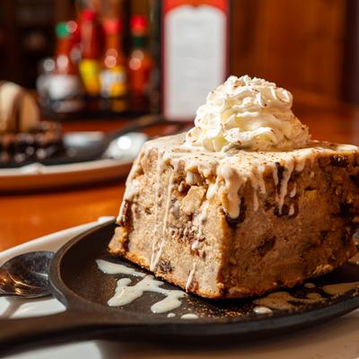 New Orleans bread pudding topped with whipped cream and sweet sauce.