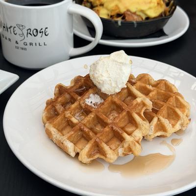 Waffle served with a dollop of whipped cream and syrup.
