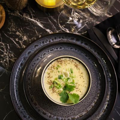 Coconut curry garnished with herbs, and served in a dark ceramic bowl.