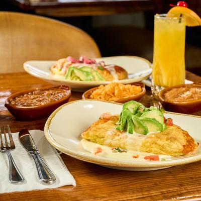 Two breakfast dishes served on the table with sides and a glass of orange juice.