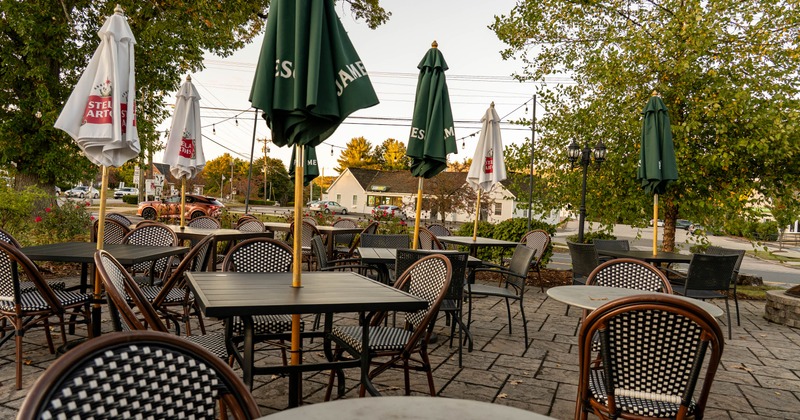 Outdoor café patio with tables, chairs, and closed umbrellas