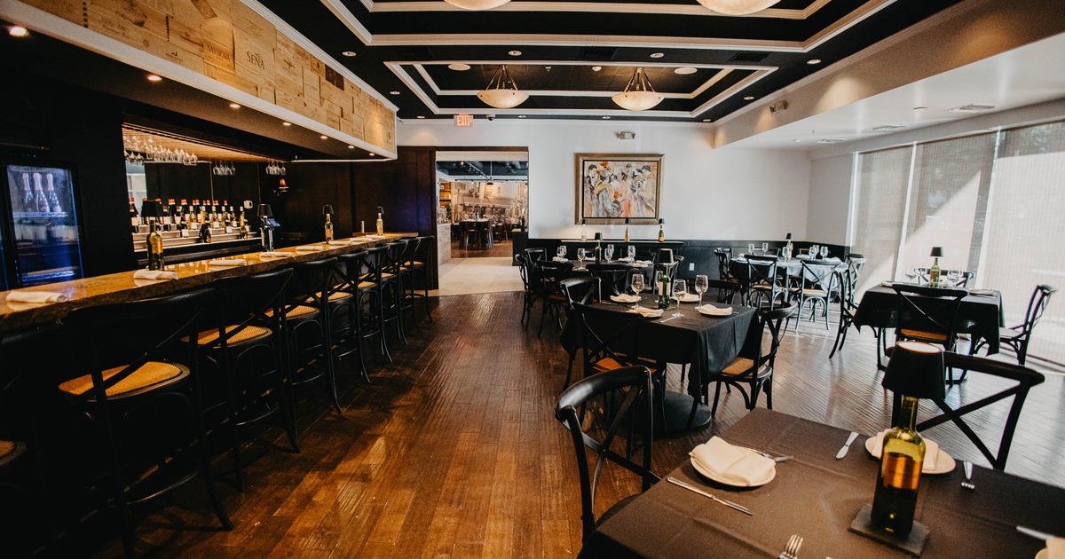 Upscale restaurant interior with dining tables, a bar counter and soft lighting.