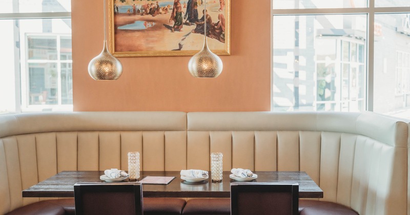 A restaurant booth with cream upholstery, a wooden table