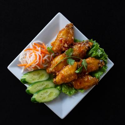Chicken wings with pickled vegetables and fresh cucumber slices.