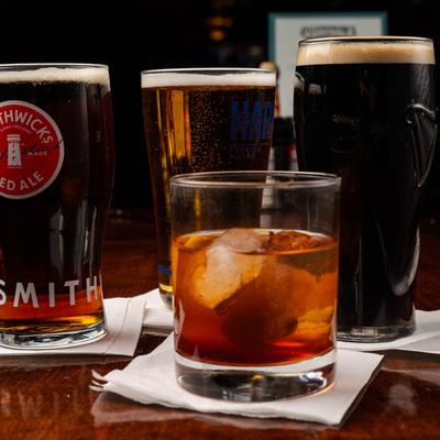 A glass of old fashioned whiskey and glasses of beer in the background