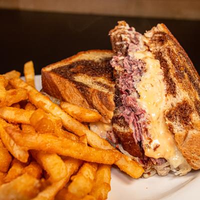 Reuben sandwich paired with seasoned fries, close-up.