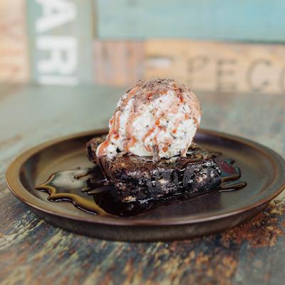 Chocolate brownie with a scoop of ice cream and chocolate syrup.