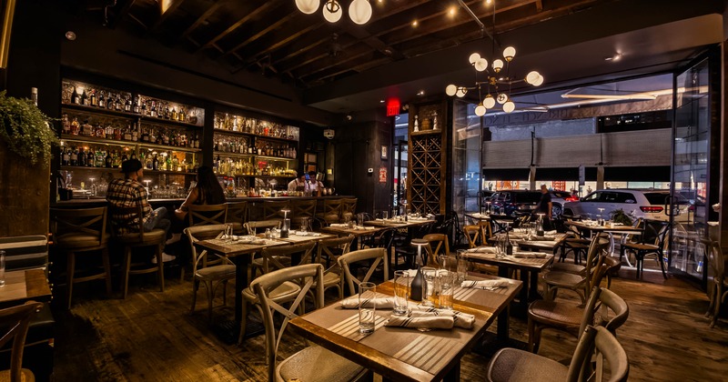 Interior, wooden beams, a well stocked bar, and tables set for dining