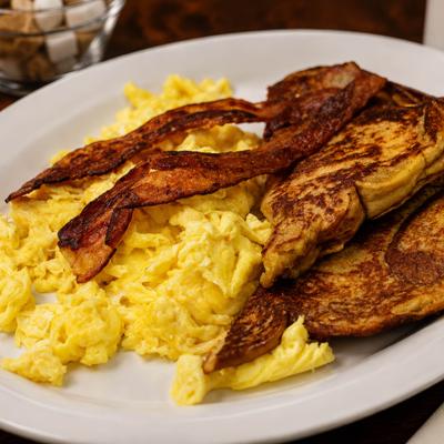 Breakfast plate with scrambled eggs, crispy bacon strips, and toast.