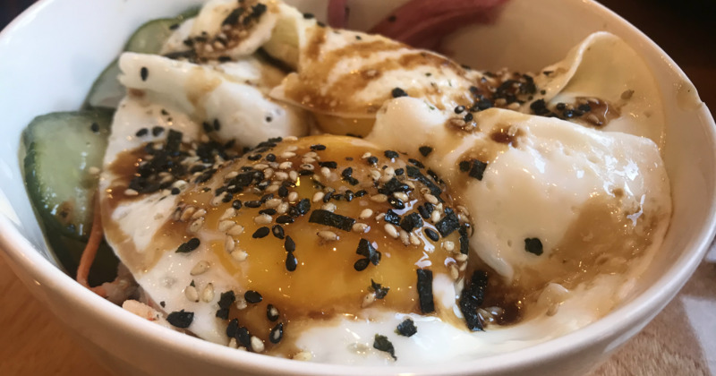 Vegetables topped with fried egg and sesame seeds