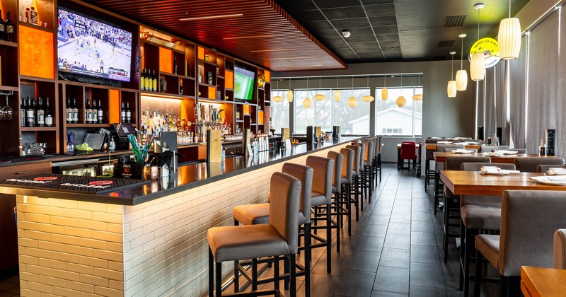 Interior featuring a bar, stools, wooden tables, and pendant lights