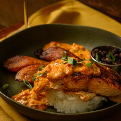 Salmon topped with spicy tomato cream, served with rice, beans and plantains.