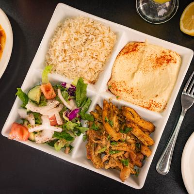 Mediterranean chicken shawarma platter with hummus, rice, and salad.