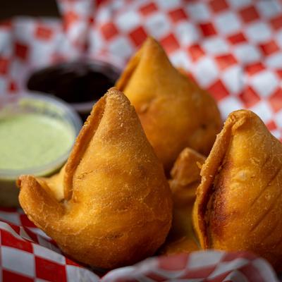 Samosas served with two dipping sauces, close-up.