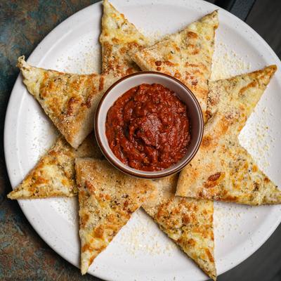 Pizza bread slices arranged around marinara dipping sauce.
