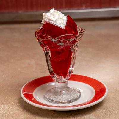 Strawberry sundae served in a ribbed glass fountainware dish.