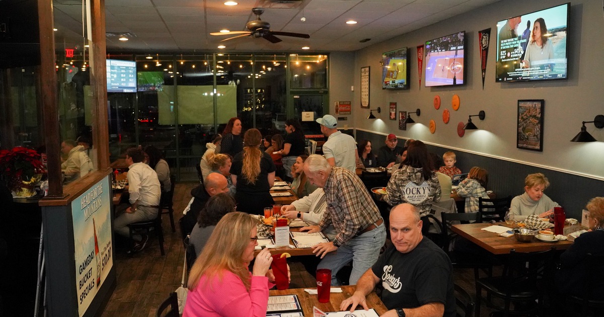 Diner area, guests, screens on walls, tables and chairs