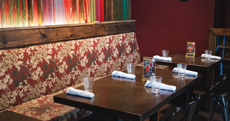 Cozy restaurant with dark wood tables, elegant floral bench seating