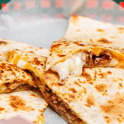 Close-up of a sliced chicken quesadilla with melted cheese.