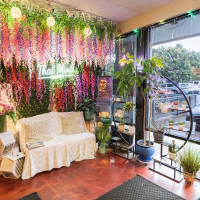 Sofa surrounded by hanging floral arrangements and plant.