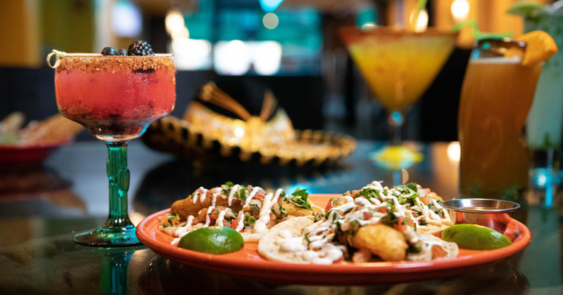 Red cocktail next to the plate with delicious food
