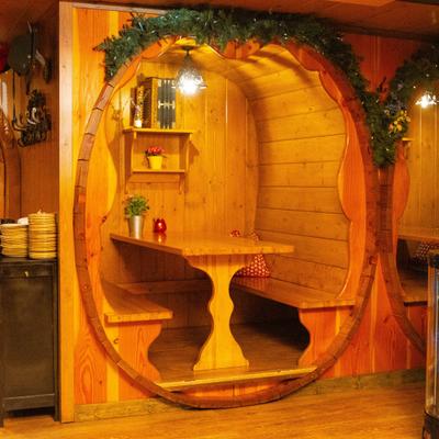 Interior, cozy wooden seating area resembling a barrel, with a table and benches inside.