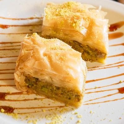 Two pieces of baklava with roasted pistachios.
