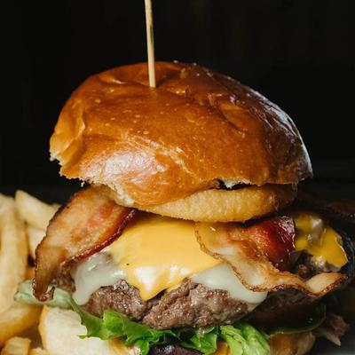 Stacked burger with mozzarella, American cheese, onion rings, bacon, and lettuce.