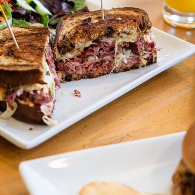 Halved Reuben sandwich served alongside a small side.