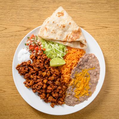 Marinated pork chunks served with tomato salsa, lettuce, rice, beans, and tortillas.