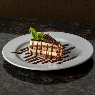A slice of tiramisu cake on a drizzled white plate.