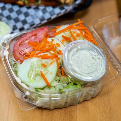 Fresh salad with cucumbers, tomatoes, carrots, lettuce and dressing cup.