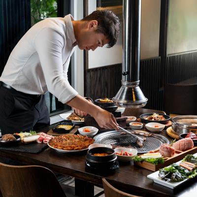 A staff member cooking food on a full table.