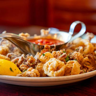 Fried calamari plate with marinara and lemon wedges, close up.