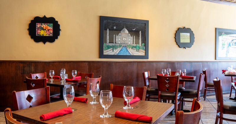 Restaurant interior with wooden tables set with empty glasses and red napkins