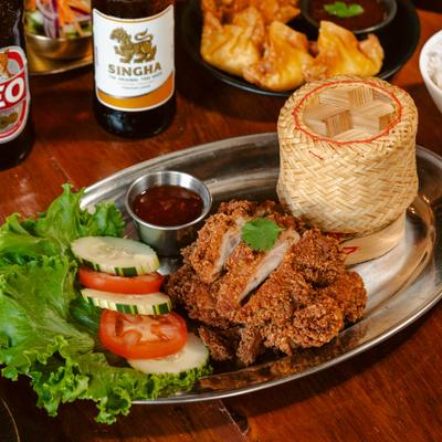 Fried chicken served with sticky rice, fresh greens, and a dipping sauce.