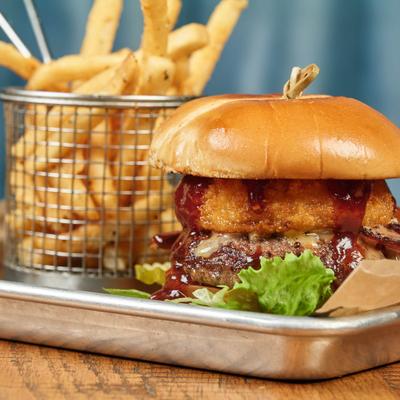 Hamburger - barbecue sauce, lettuce, cheese, bacon and a fried onion ring; fries in a metal basket