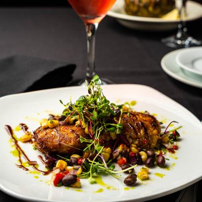 Crab cakes topped with microgreens and corn salsa.