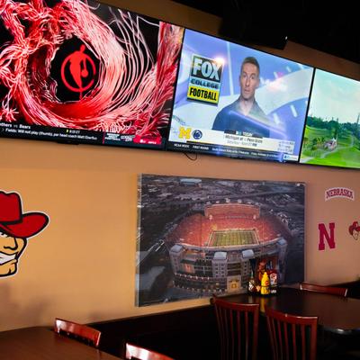 Dining area, tables by a brick wall with TV screens.