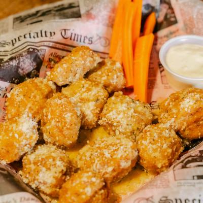 Garlic Boneless Wings served with carrot sticks and a dipping sauce.
