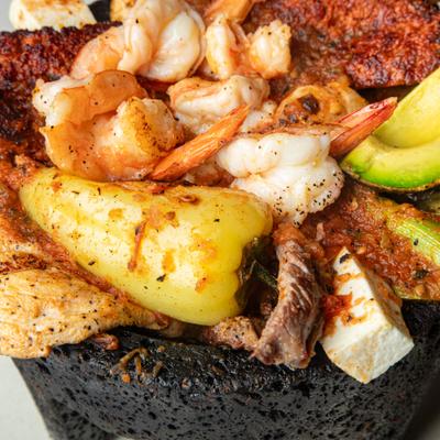 Molcajete featuring grilled steak, chicken, shrimp, chorizo, cheese and avocado.